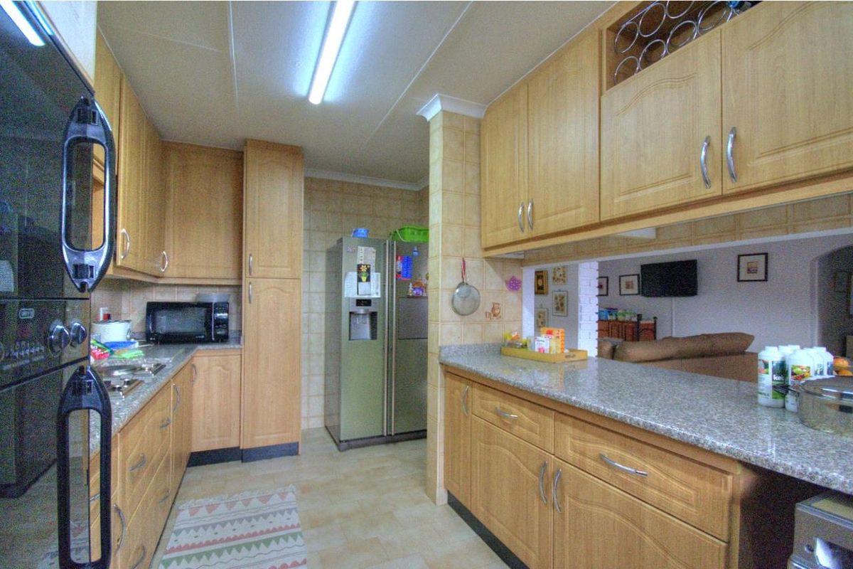 A functional kitchen featuring light wood cabinetry, granite countertops, and a breakfast bar pass-through window overlooking the adjacent living area.