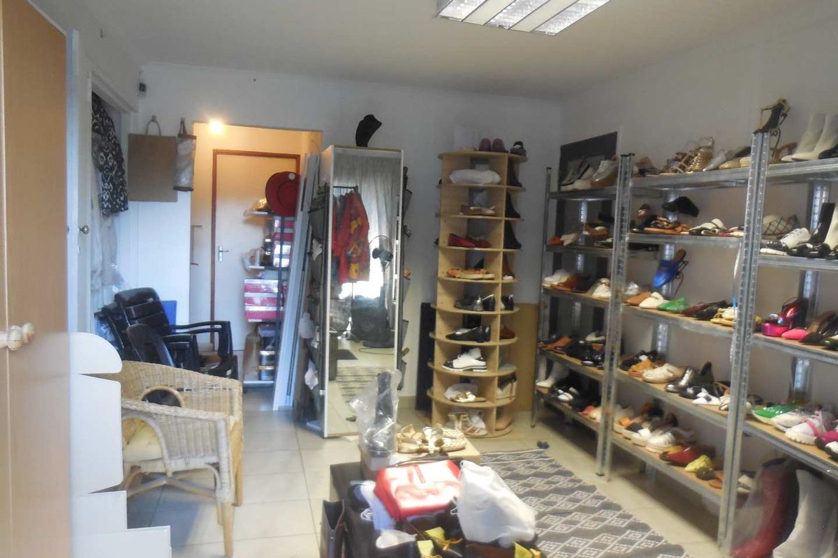 An office space currently utilized for storage, featuring tiled flooring and overhead fluorescent lighting.