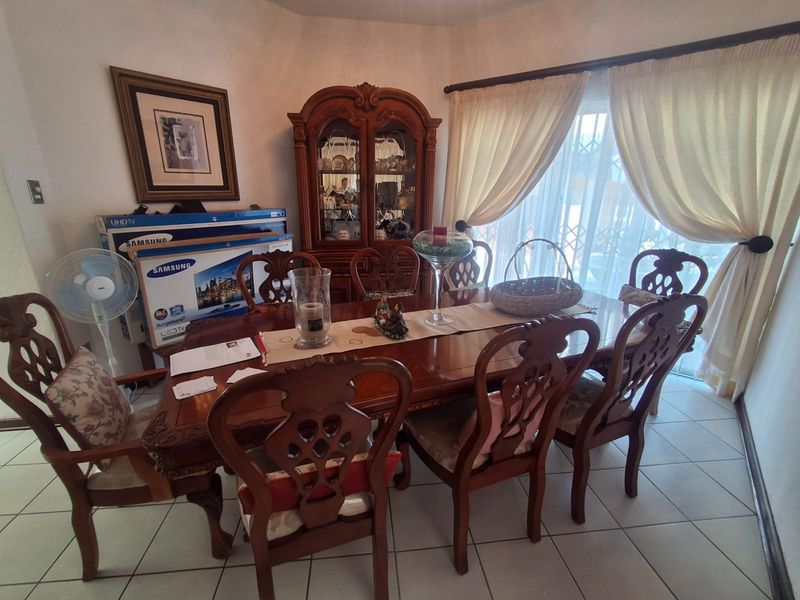 A traditional dining room featuring tiled flooring and a large sliding glass door with curtains, providing natural light to the space.