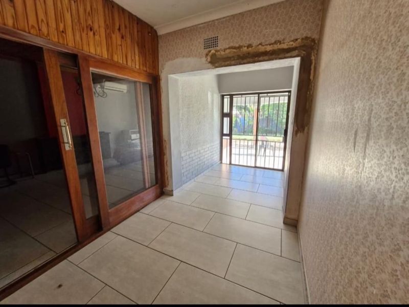 An enclosed patio area featuring tiled flooring, timber ceiling paneling, and sliding glass doors, currently requiring finishing work on the wall plastering.