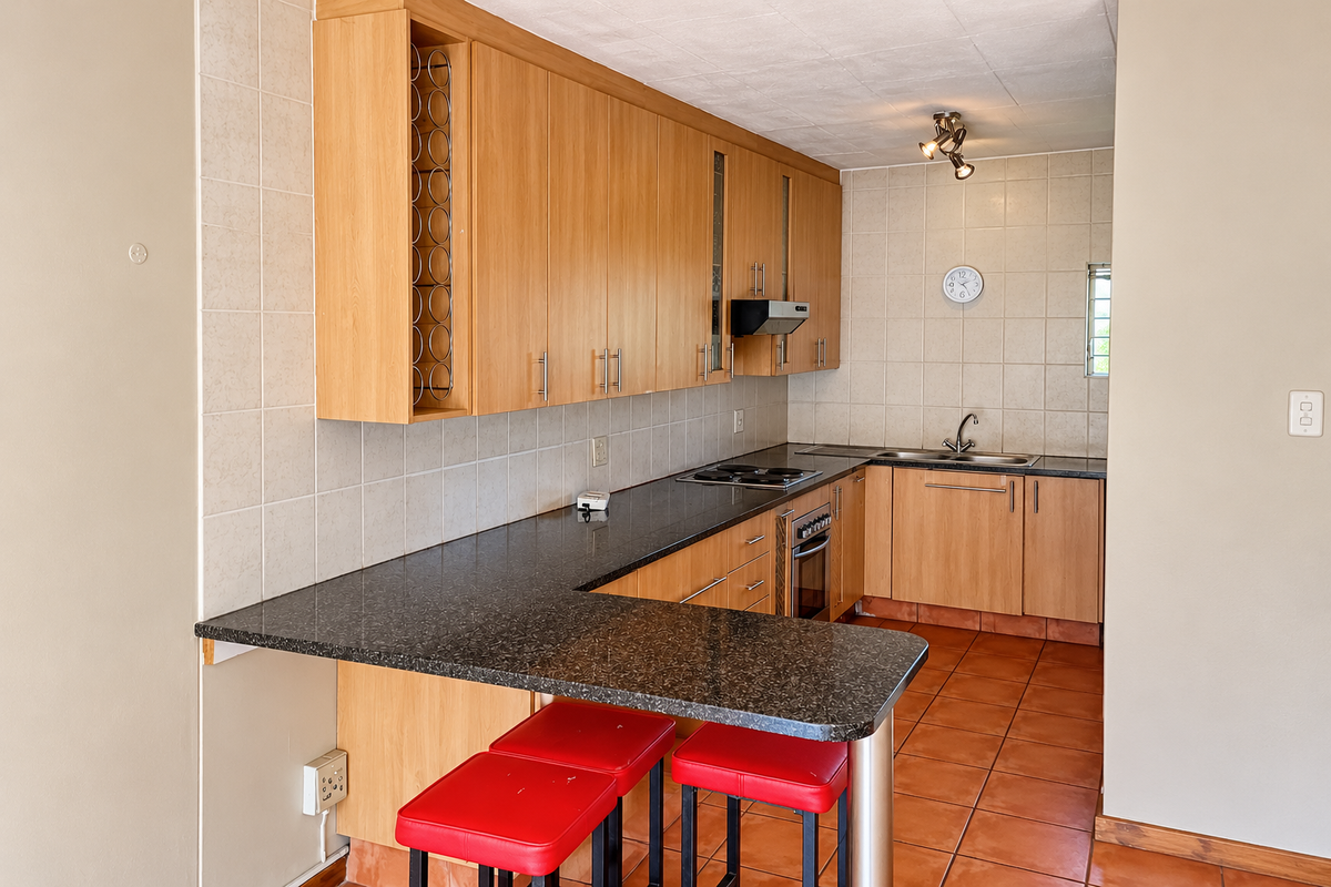 A functional kitchen featuring laminate cabinetry, granite countertops, a built-in oven and hob, and a breakfast bar with tiled flooring and backsplash.