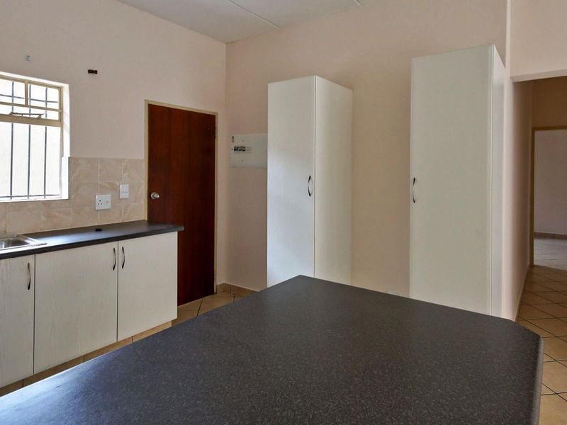 A functional kitchen featuring laminate countertops, built-in cabinetry, and tiled flooring, offering a clean and practical space ready for personalization.