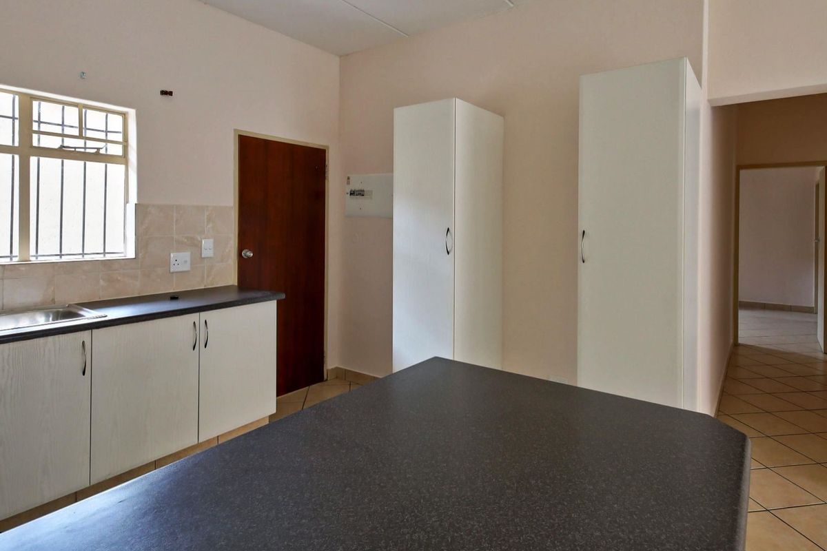 A functional kitchen featuring laminate countertops, built-in cabinetry, and tiled flooring, offering a clean and practical space ready for personalization.