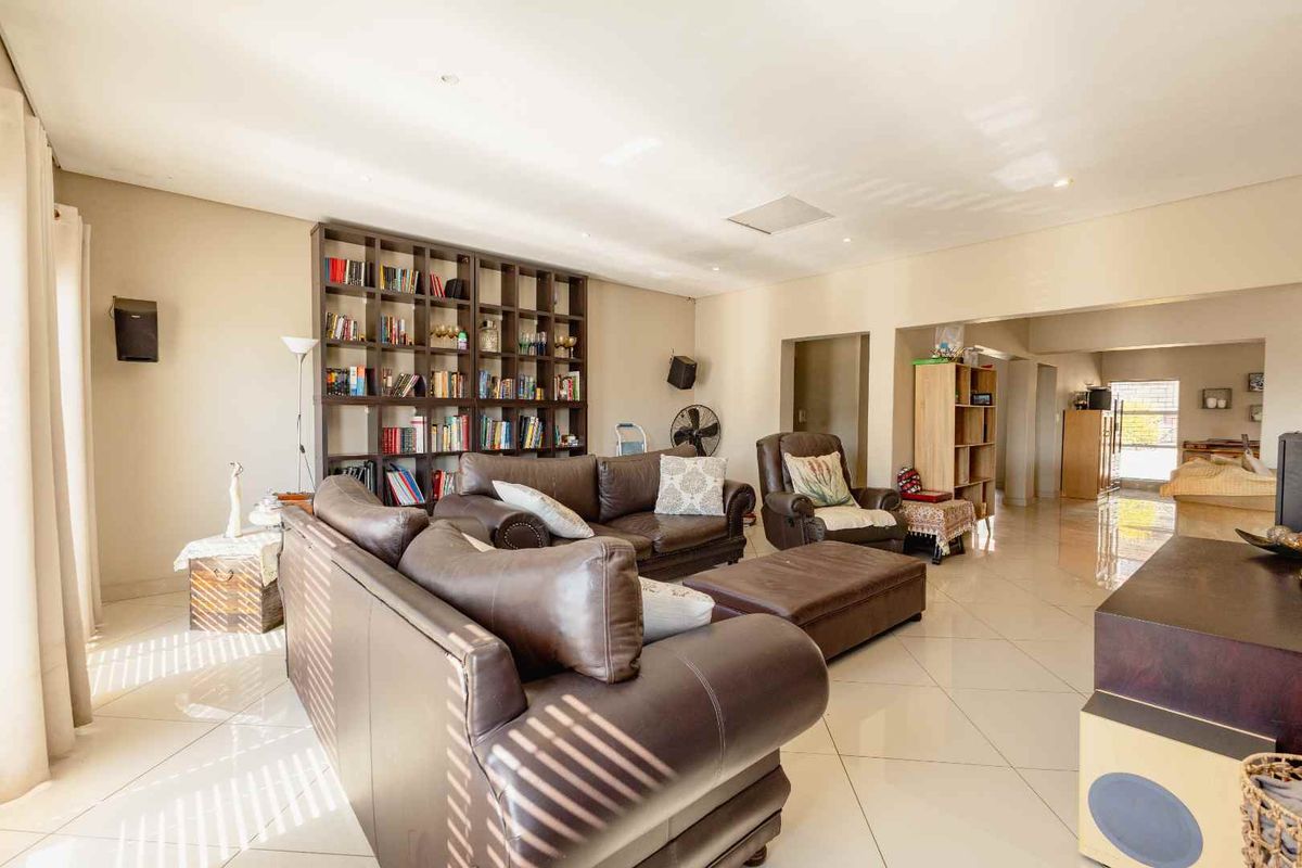Spacious living area featuring large format floor tiles, recessed lighting, and a substantial built-in shelving unit.