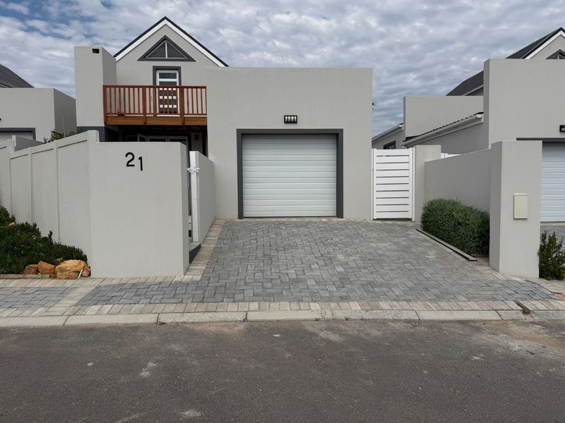 Front elevation of a modern residential property featuring a single garage, paved driveway, and an upper-level balcony with timber balustrade.