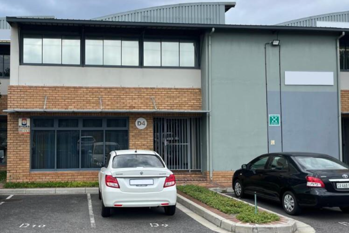 Front exterior view of an industrial unit featuring brick and painted facade, large windows, and dedicated parking bays.