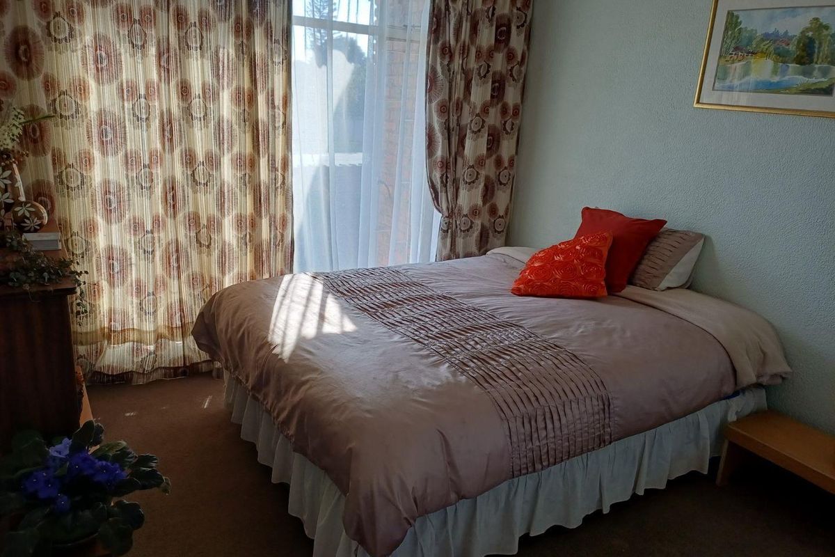 A functional bedroom featuring carpeted flooring and a sliding glass door providing natural light and access to the exterior.