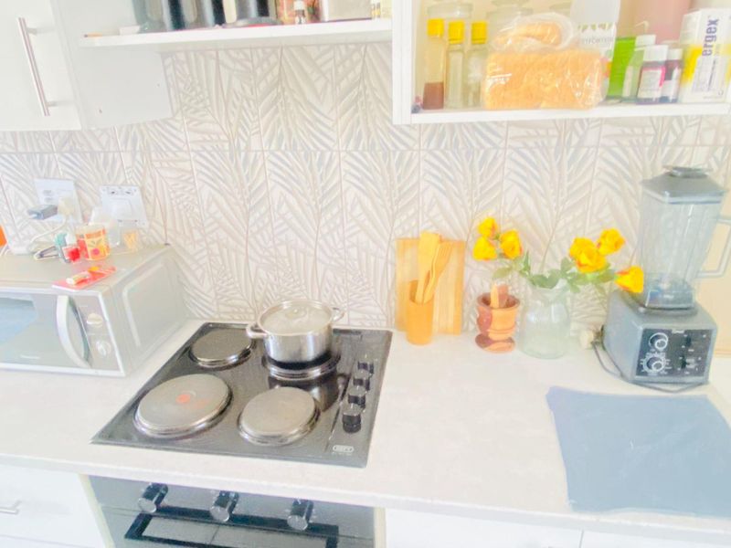 A functional kitchen area featuring a built-in oven, electric hob, patterned tile backsplash, and overhead cabinetry with ample counter space.