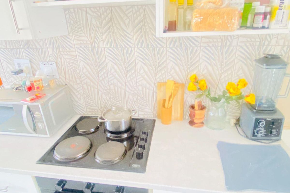 A functional kitchen area featuring a built-in oven, electric hob, patterned tile backsplash, and overhead cabinetry with ample counter space.
