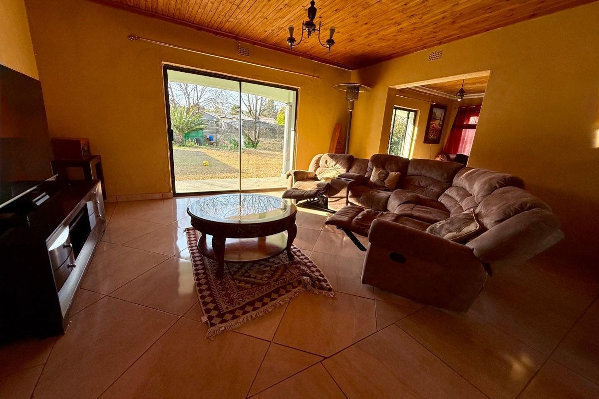 Spacious living room featuring tiled flooring, a timber-clad ceiling, and large sliding glass doors providing direct access to the rear garden.