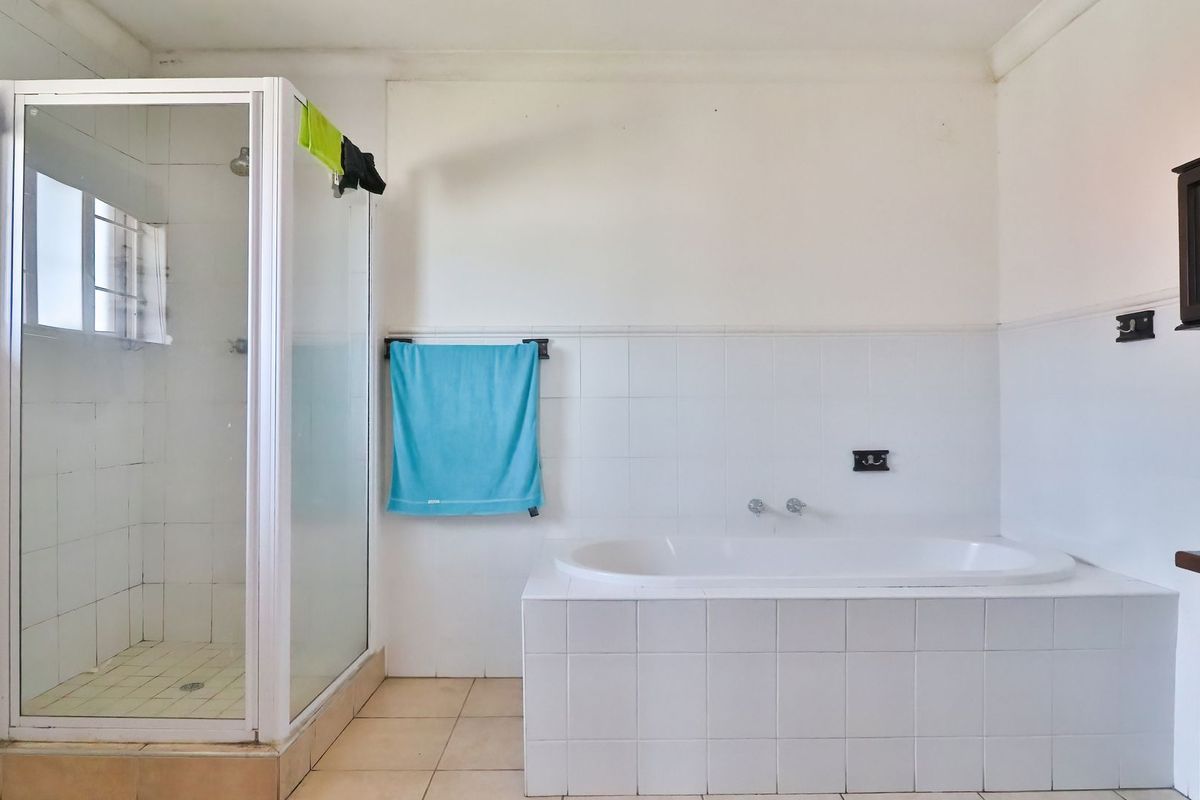 A functional bathroom featuring a white tiled built-in bathtub and a separate shower enclosure with white framing.