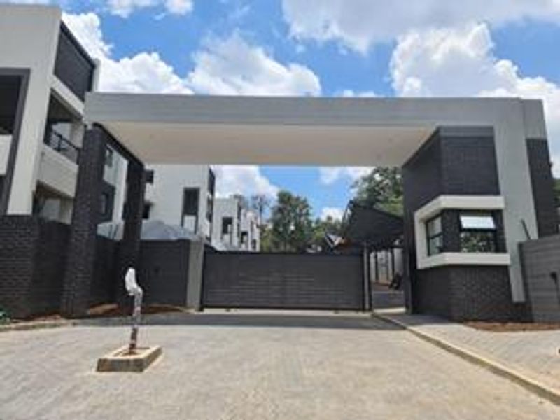 Modern apartment complex entrance featuring a secure gated access point, guard house, and contemporary brick and render facade design.