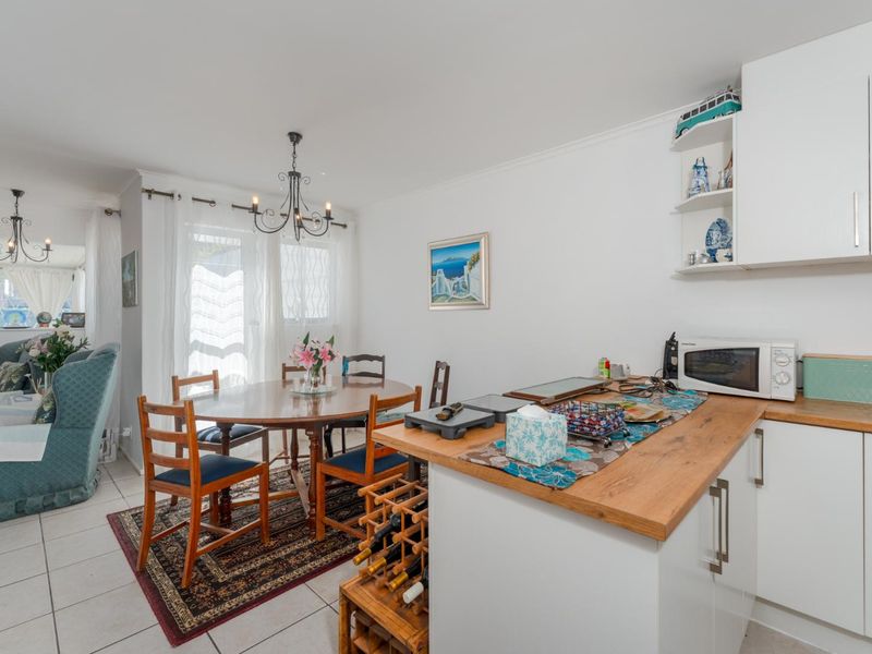 Open-plan kitchen and dining area featuring white cabinetry, wooden countertops, and tiled flooring, creating a functional and connected living space.