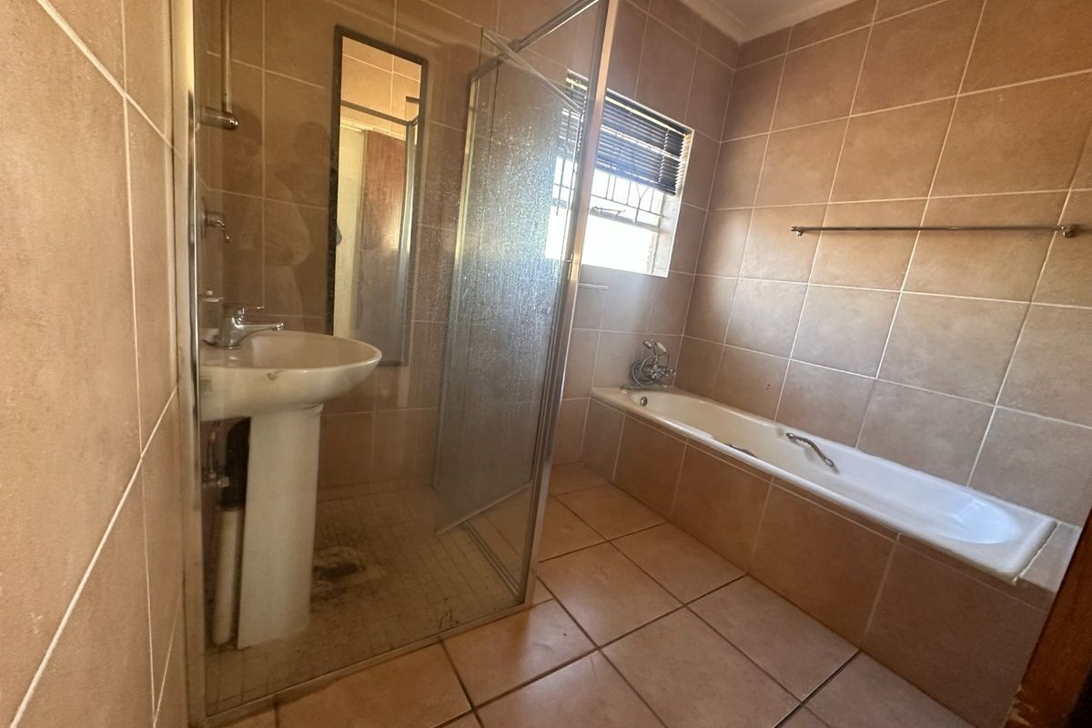 A functional bathroom featuring a pedestal basin, a glass-enclosed shower, and a built-in bathtub with neutral wall and floor tiling.
