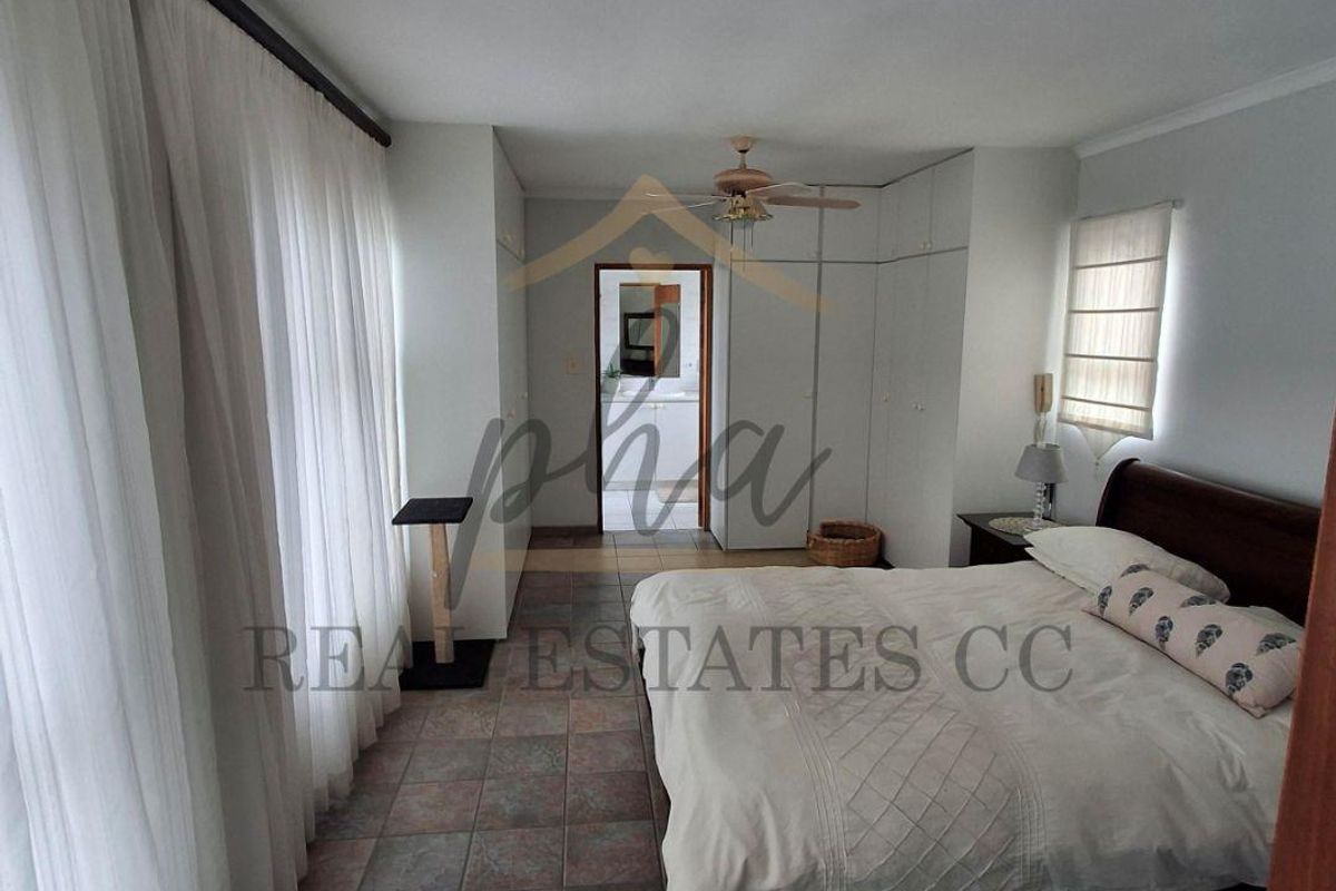 Spacious bedroom featuring tiled flooring, built-in cupboards, a ceiling fan, and direct access to an en-suite bathroom.