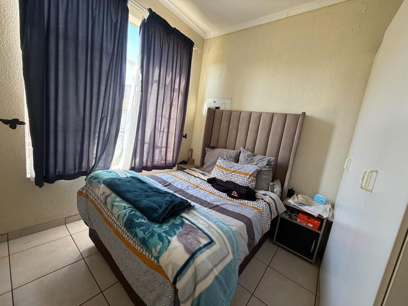 A functional bedroom featuring tiled flooring, a built-in wardrobe, and coved ceiling details, offering a neutral base for potential interior updates.
