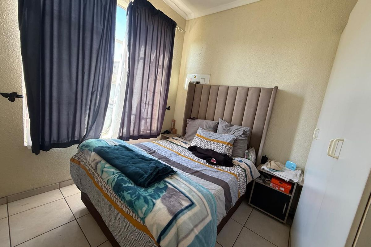A functional bedroom featuring tiled flooring, a built-in wardrobe, and coved ceiling details, offering a neutral base for potential interior updates.
