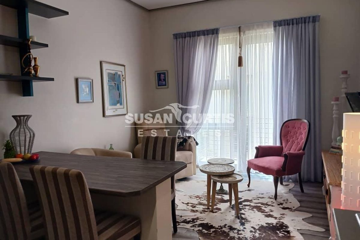 A well-maintained living area featuring laminate flooring, built-in shelving, and a large sliding glass door providing natural light.