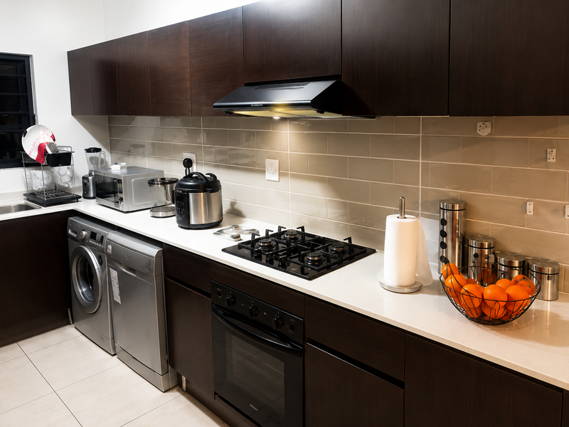 Modern kitchen featuring dark wood cabinetry, stone countertops, subway tile backsplash, and integrated appliances including a gas hob, oven, and extractor fan.