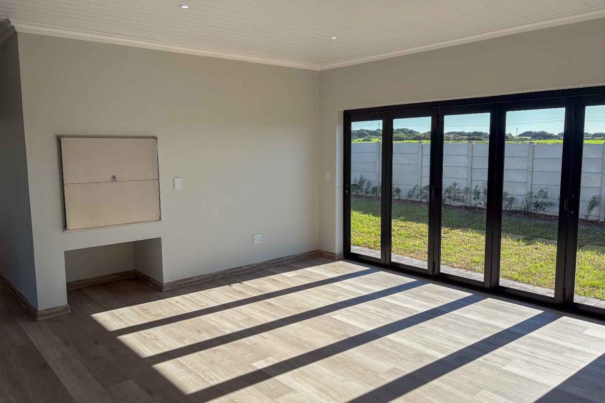 Bright and spacious living area featuring modern wood-look flooring, recessed ceiling lighting, and large black-framed folding doors opening to the rear garden.