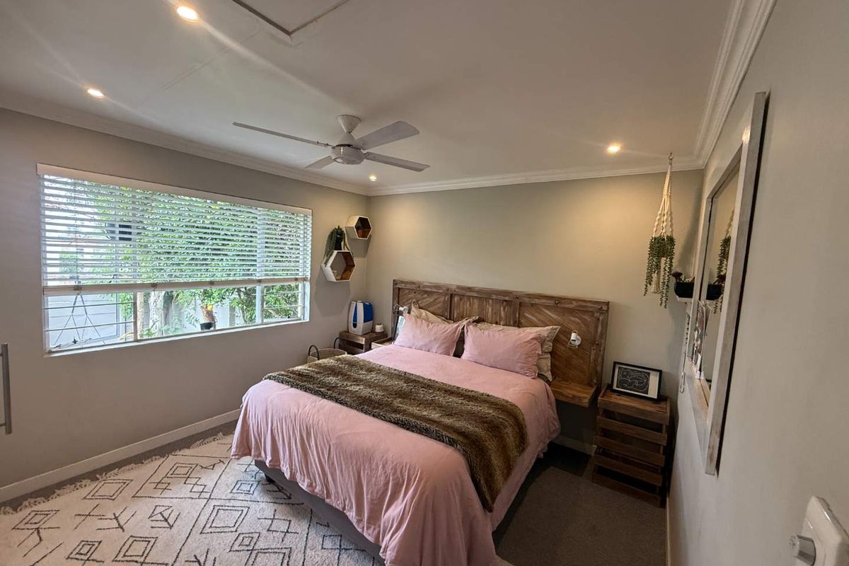 A well-maintained bedroom featuring recessed downlights, a ceiling fan, and crown molding, with large windows fitted with venetian blinds.