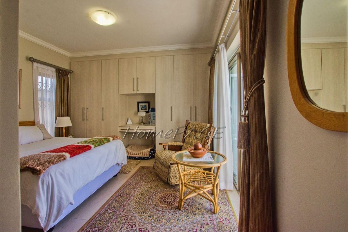 A well-lit bedroom featuring extensive built-in cabinetry with an integrated desk area and sliding glass doors providing access to the exterior.