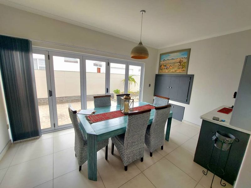 Dining area featuring large glass stacker doors opening to a paved patio, tiled flooring, and built-in cabinetry.