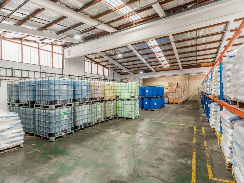 Spacious industrial warehouse featuring high ceilings with exposed steel trusses, integrated skylights, and heavy-duty racking systems on durable concrete flooring.