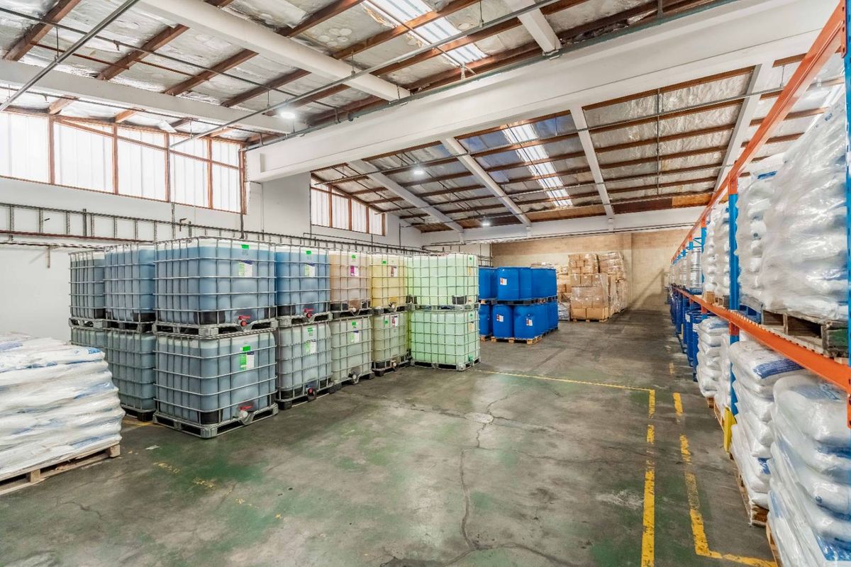 Spacious industrial warehouse featuring high ceilings with exposed steel trusses, integrated skylights, and heavy-duty racking systems on durable concrete flooring.