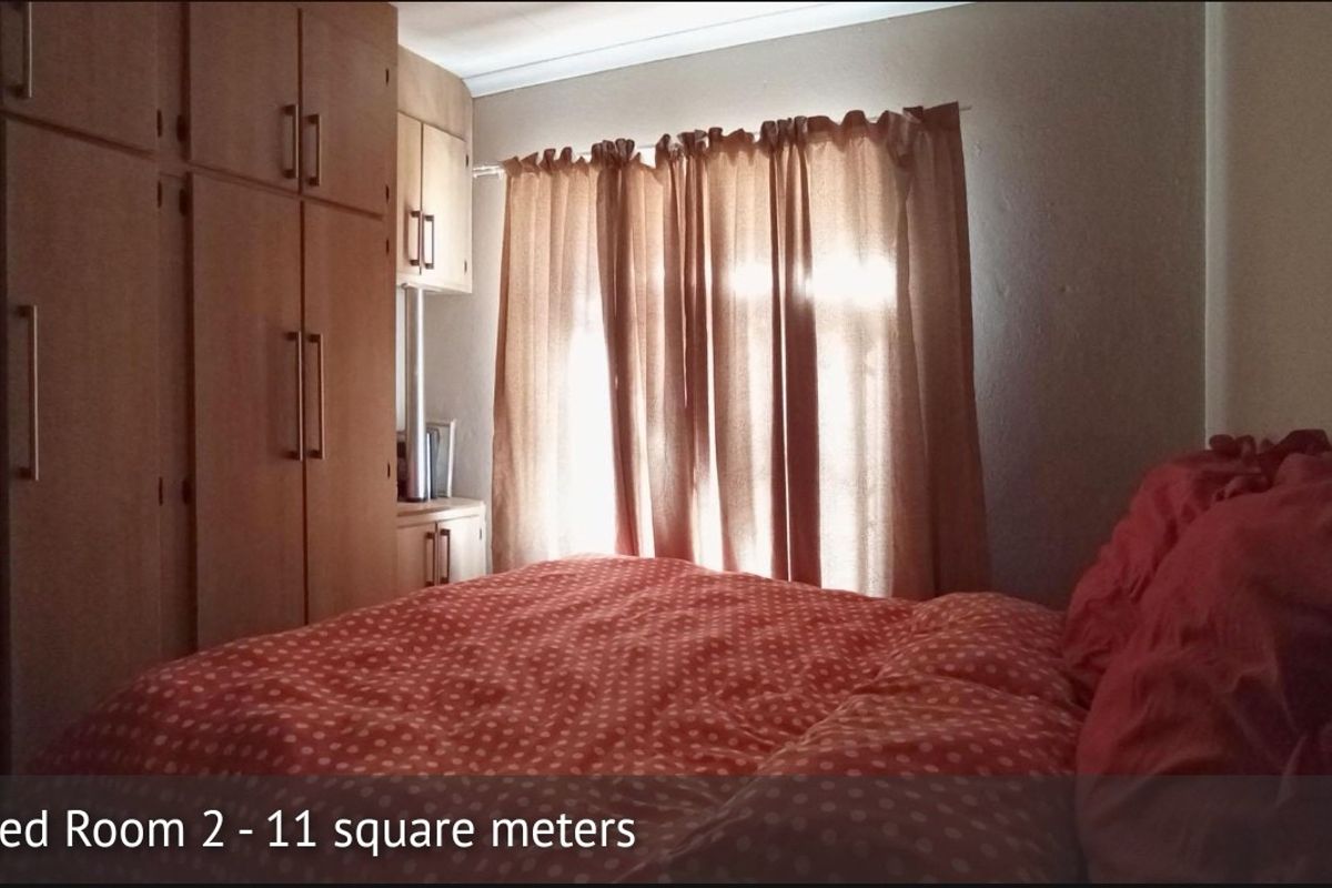 A bedroom featuring built-in wooden cupboards and natural light through the window.