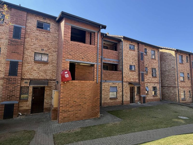 Exterior view of a multi-story apartment complex featuring face brick construction, paved walkways, and multiple balcony access points.