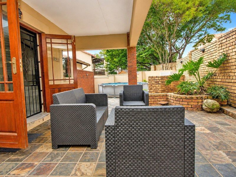 A covered patio area featuring slate tile flooring, brick boundary walls, and a raised brick planter, providing a functional outdoor entertainment space.