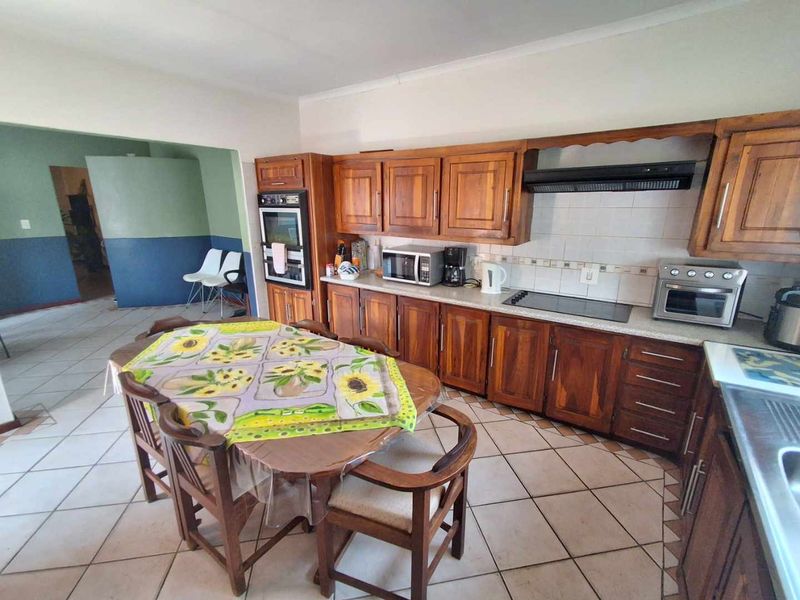 Open-plan kitchen and dining area featuring traditional wooden cabinetry, built-in oven, ceramic hob, and tiled flooring throughout.