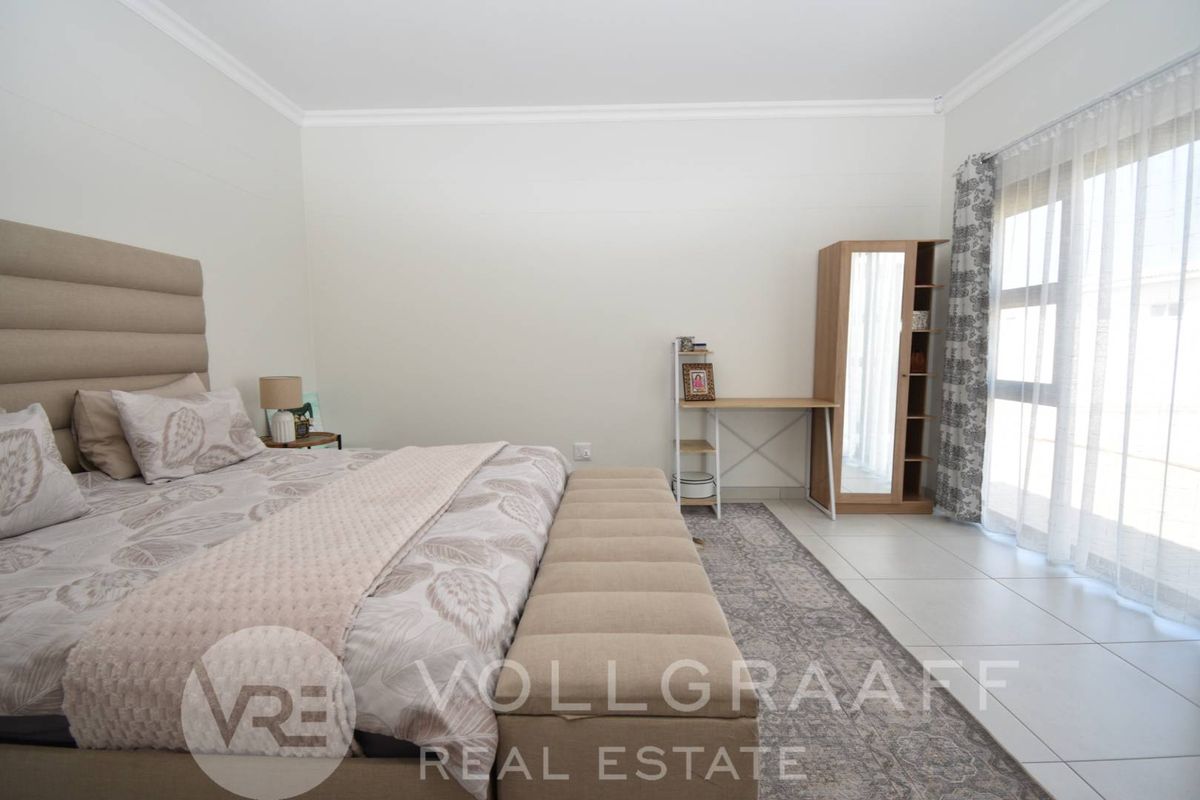 A bright and spacious bedroom featuring neutral tiled flooring and a large sliding glass door providing direct access to the exterior.