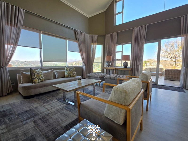 Spacious living room featuring a vaulted ceiling, expansive windows with scenic views, and direct access to an outdoor patio area.