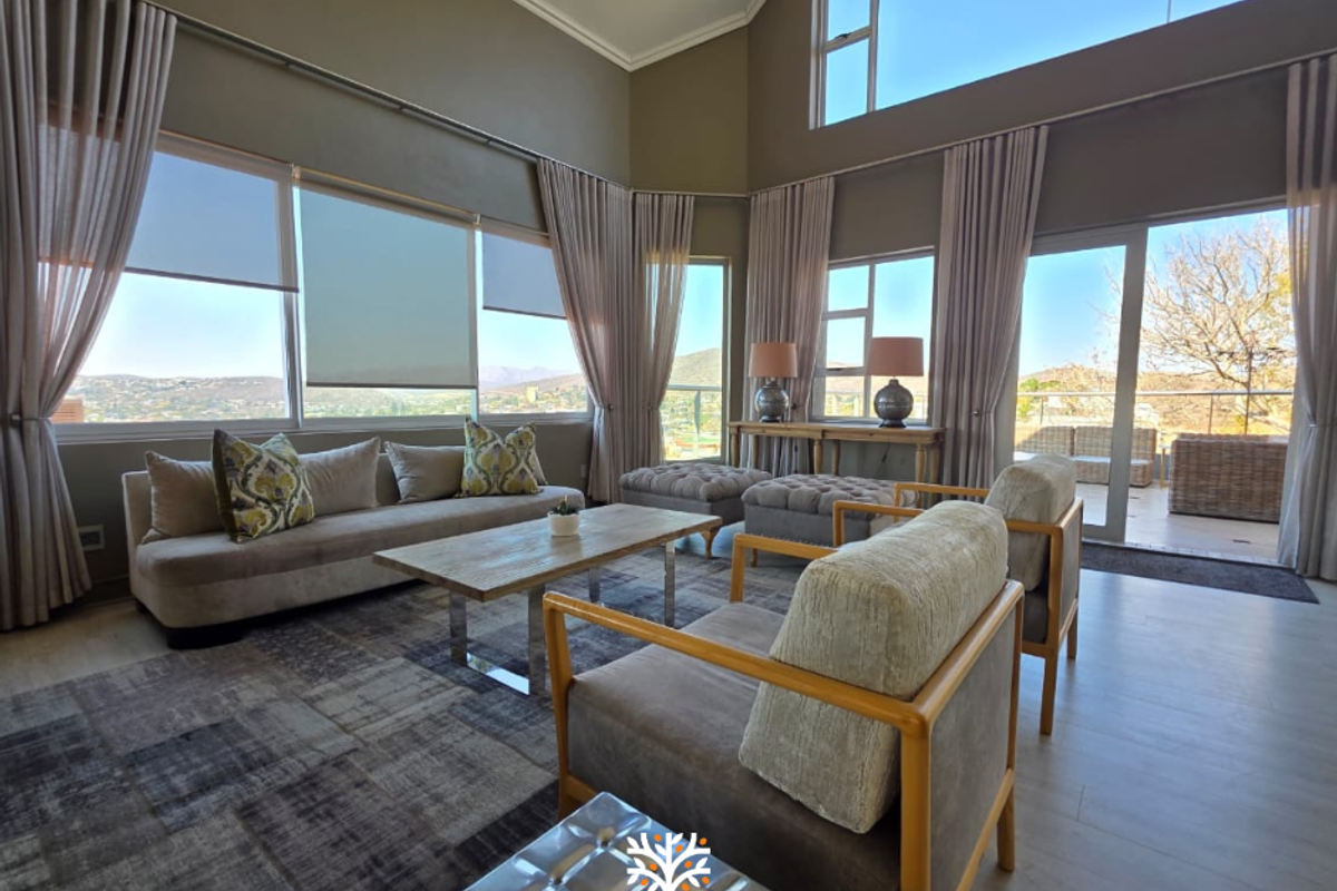 Spacious living room featuring a vaulted ceiling, expansive windows with scenic views, and direct access to an outdoor patio area.