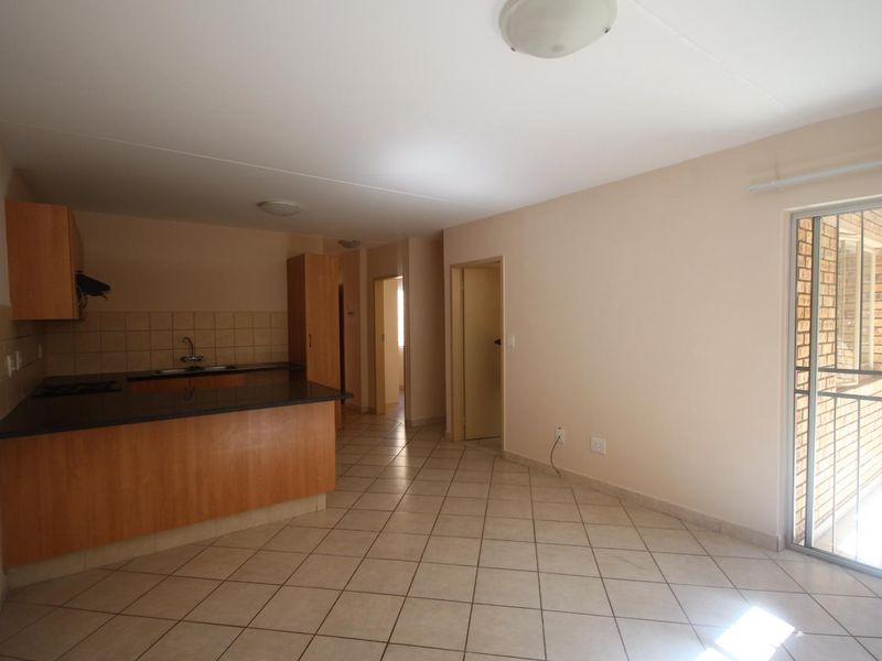 Open plan living area featuring a functional kitchen with granite countertops, tiled flooring, and direct access to a balcony through a sliding glass door.