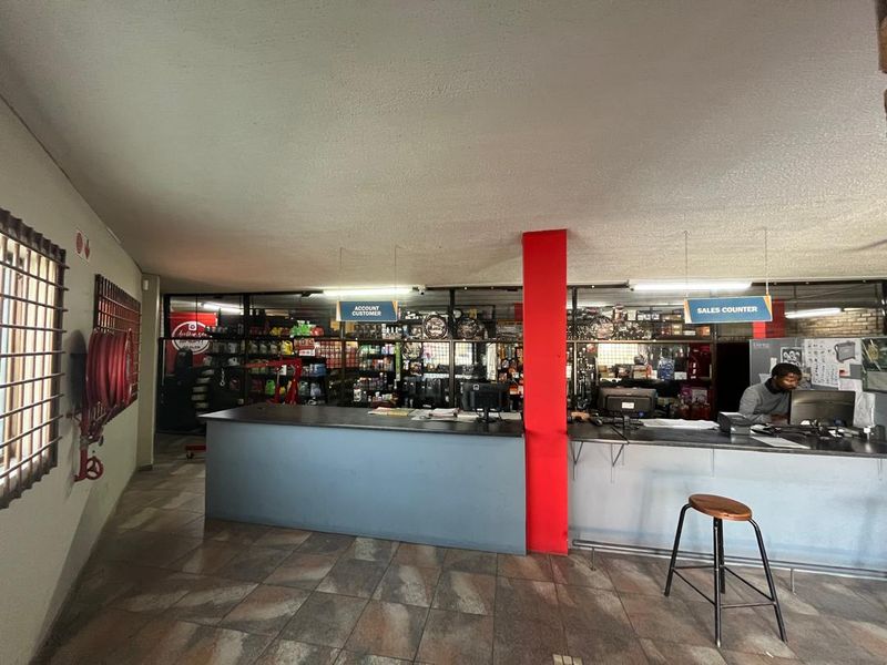 Commercial office space featuring a functional sales counter, tiled flooring, security window bars, and integrated lighting, suitable for retail or service operations.