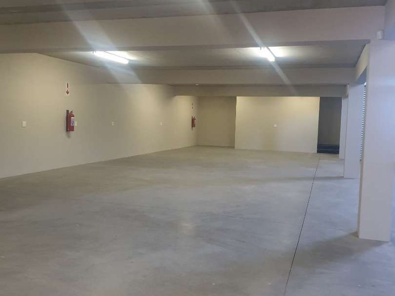 A spacious, open-plan industrial utility area featuring polished concrete flooring, exposed concrete ceilings, and functional overhead lighting.