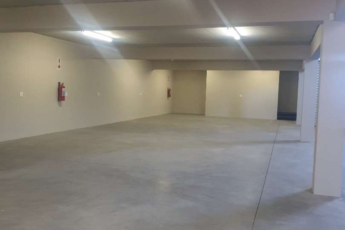 A spacious, open-plan industrial utility area featuring polished concrete flooring, exposed concrete ceilings, and functional overhead lighting.