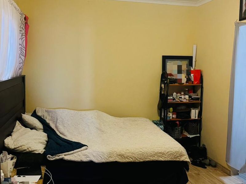 A functional bedroom featuring tiled flooring and neutral wall finishes, providing a blank canvas for potential interior updates and styling.