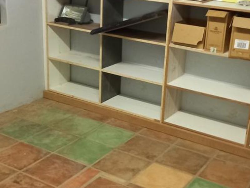 A utility space featuring a large built-in shelving unit and multi-colored ceramic floor tiles.