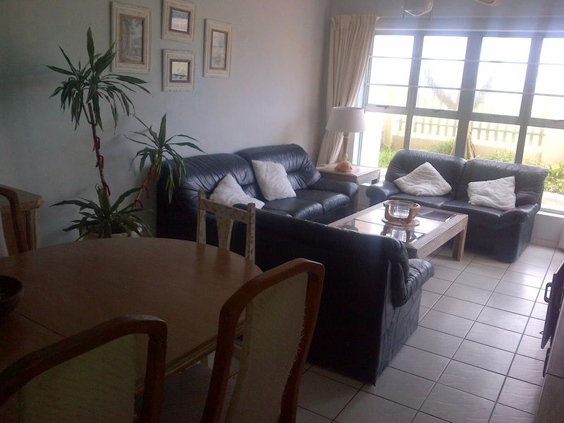 An open-plan living and dining area featuring tiled flooring and a large window providing natural light.