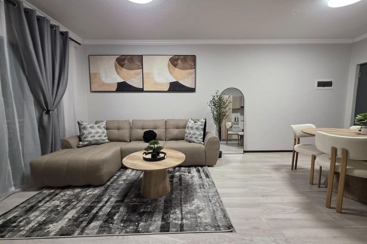 A well-maintained open-plan living and dining area featuring light-toned laminate flooring and neutral wall finishes.