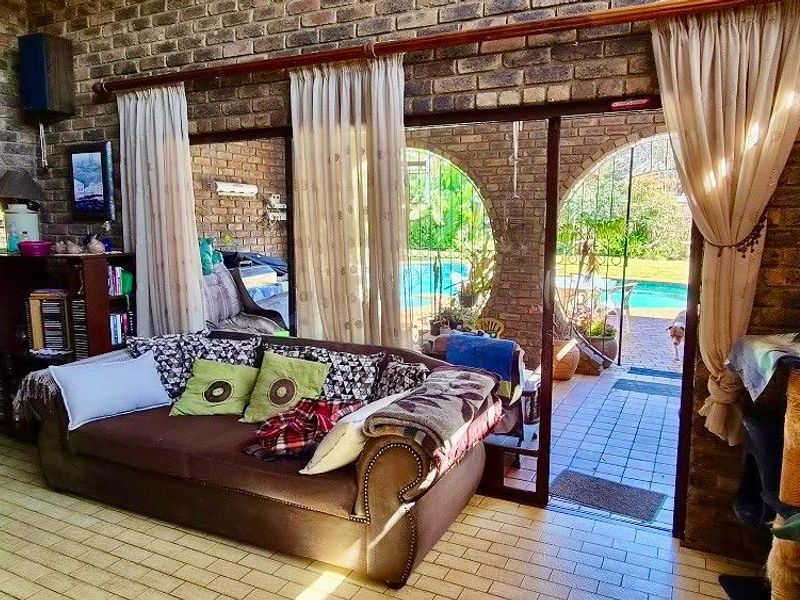 Spacious living area featuring rustic exposed brick walls, tiled flooring, and large sliding glass doors providing direct access to the outdoor pool area.