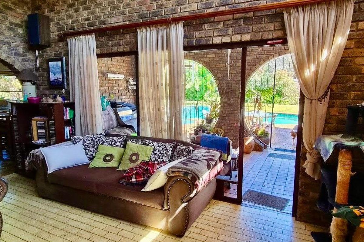 Spacious living area featuring rustic exposed brick walls, tiled flooring, and large sliding glass doors providing direct access to the outdoor pool area.