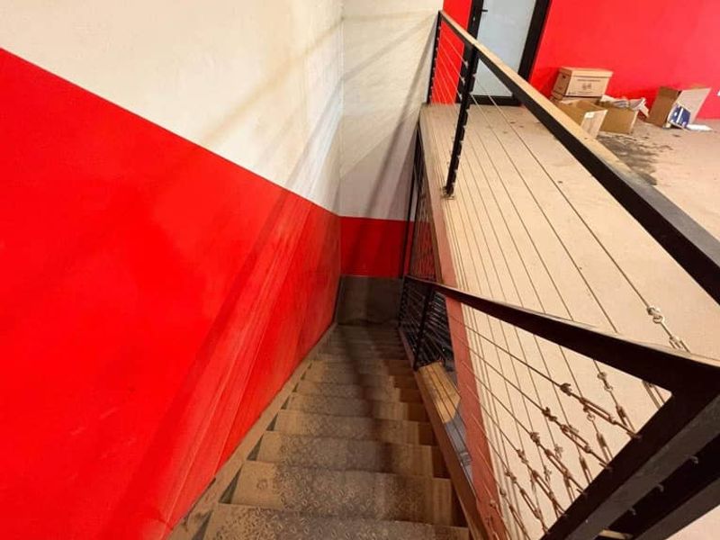 Industrial style staircase leading to a mezzanine level, featuring metal construction and a safety railing.