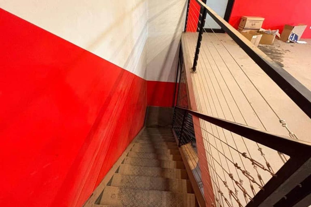 Industrial style staircase leading to a mezzanine level, featuring metal construction and a safety railing.