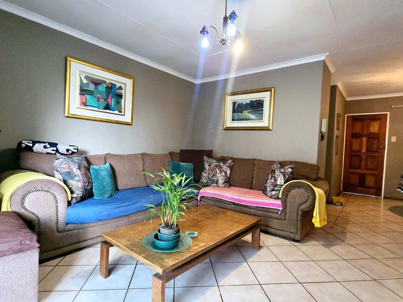A spacious living room featuring neutral wall tones, tiled flooring, and a coved ceiling, providing a comfortable and functional living area.