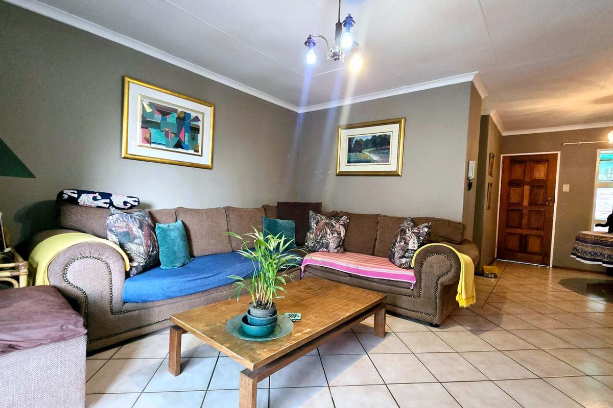 A spacious living room featuring neutral wall tones, tiled flooring, and a coved ceiling, providing a comfortable and functional living area.